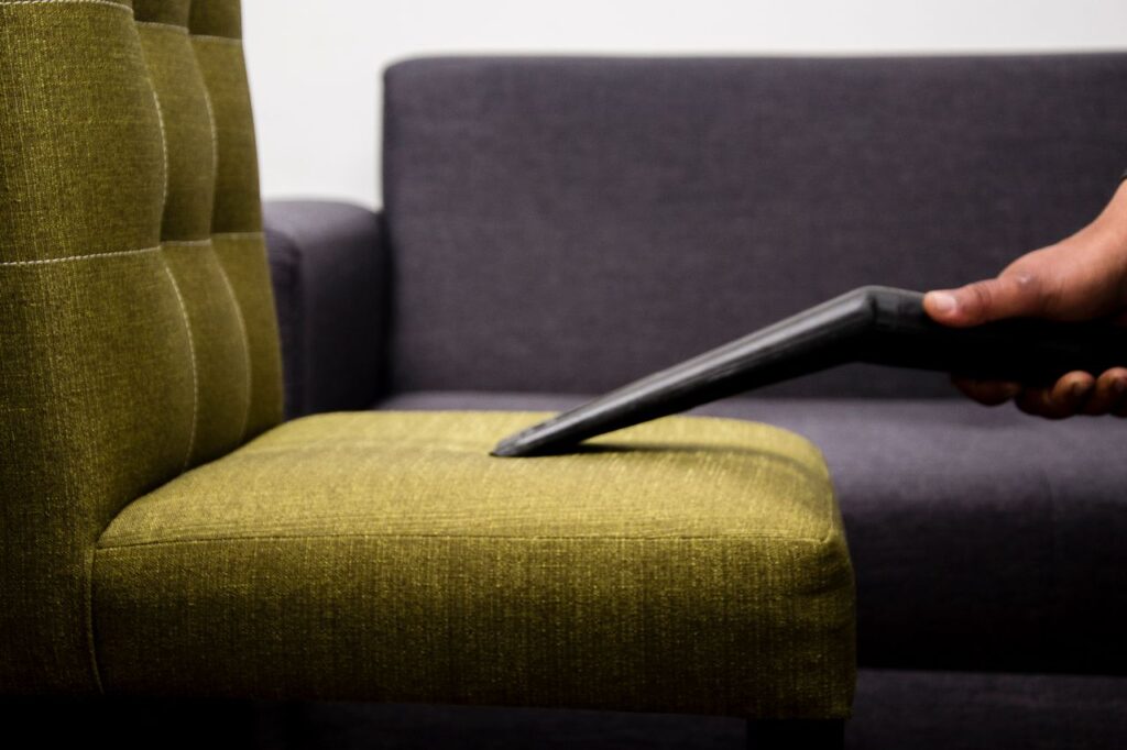 Close-up of a professional cleaner vacuuming a sofa in a client's living room